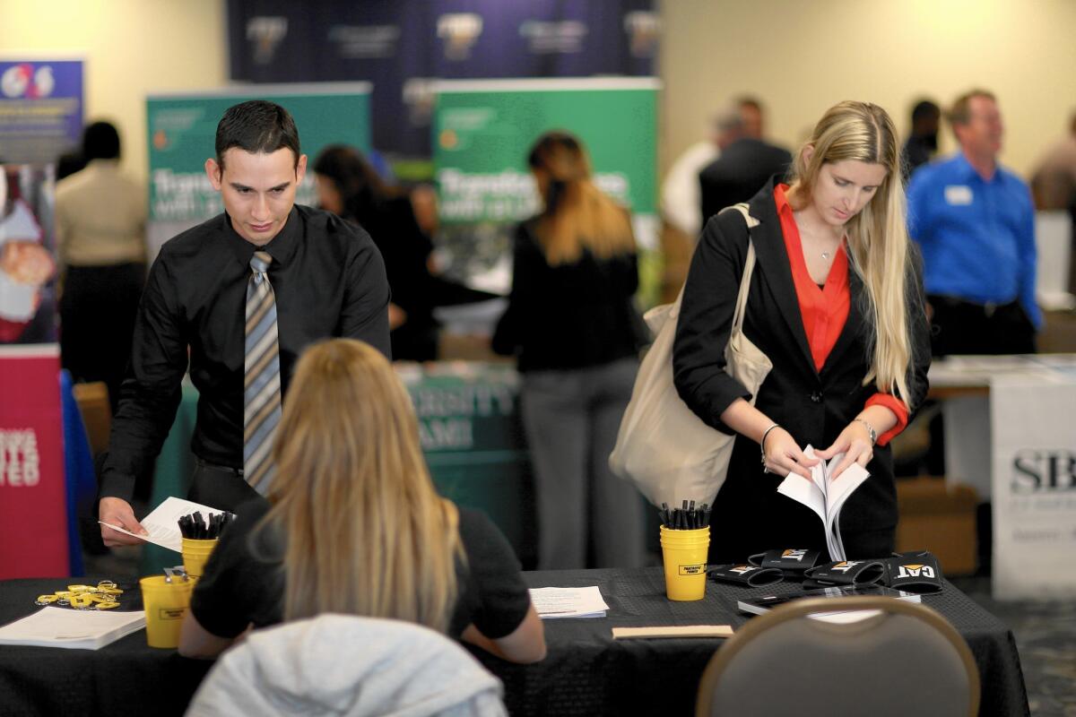 Antonio Sandoval and Pamela Springle search for positions in the civilian workforce at a veterans jobs fair in Miami this year.