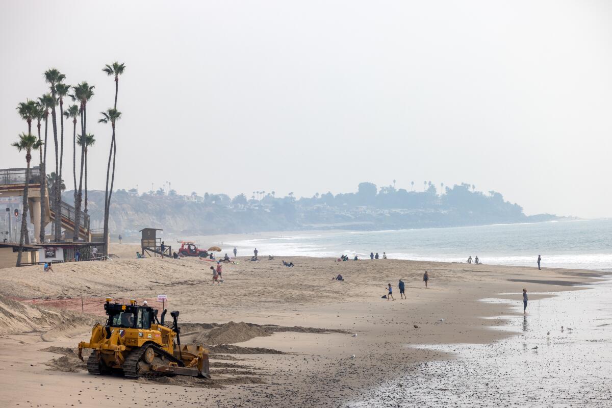 A dozer shovels dredged sediment onto San Clemente's beach.