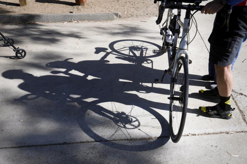 June Clark, 86, a resident of Cypress Court, a senior living community, and Dave White, president of the Blind Stokers Club are silhouetted on the ground after June completed her first bicycle ride ever, when she rode tandem with Dave at Kit Carson Park, September 19, 2019, in Escondido, California.