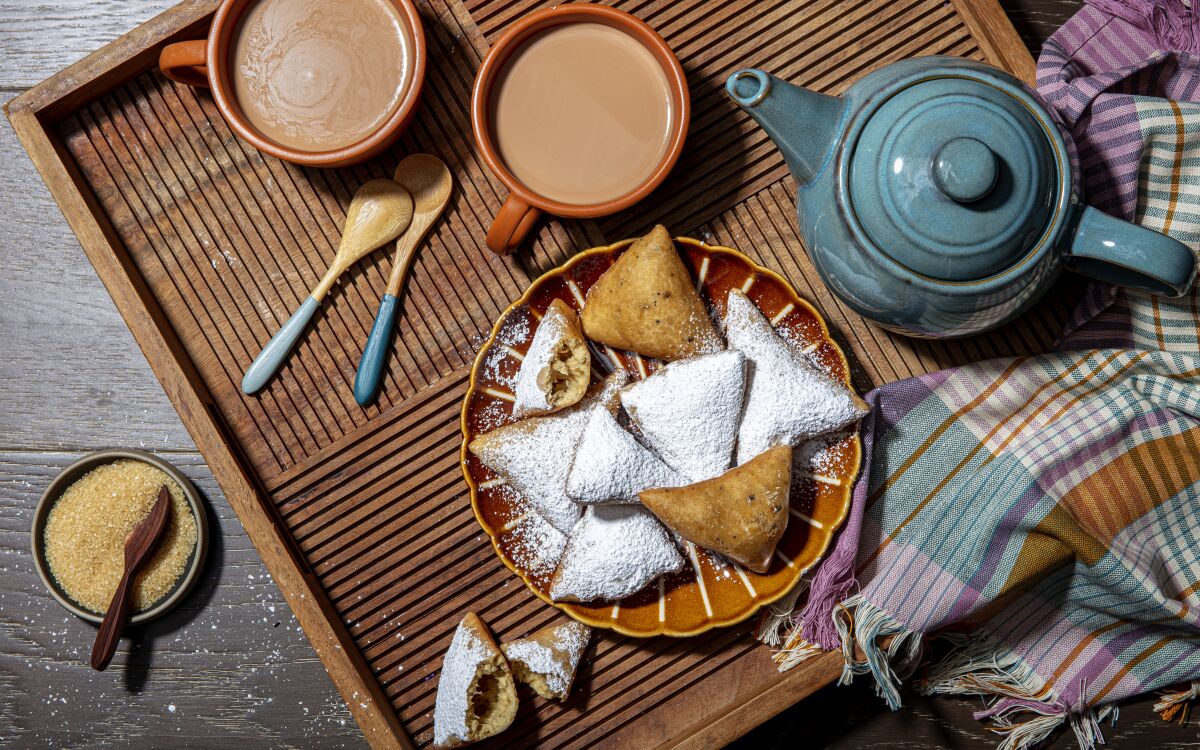 East African doughnuts called mandazi, blanketed in powdered sugar are served with fragrant chai.