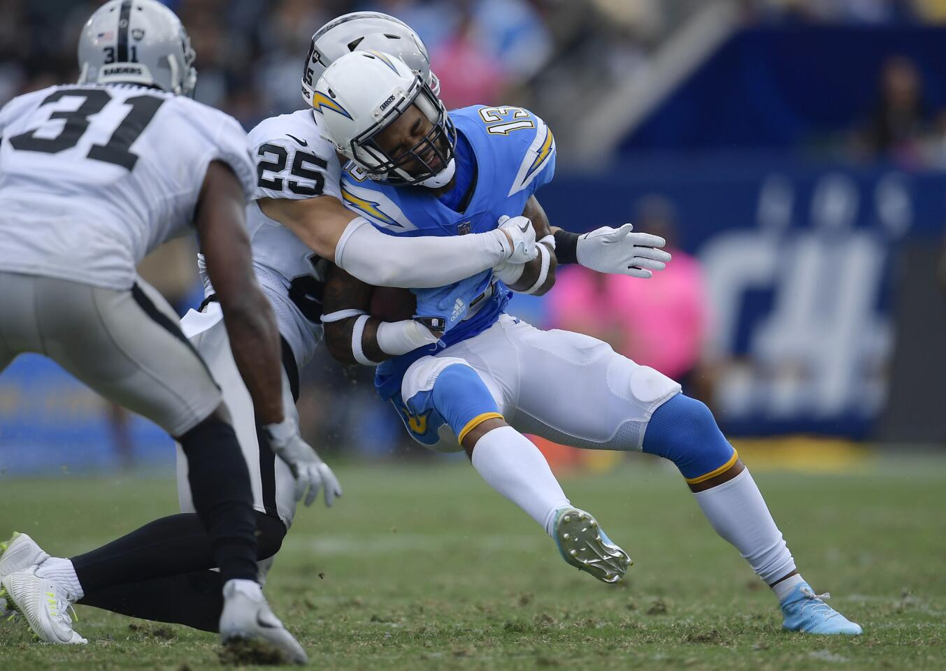 Los Angeles Chargers wide receiver Keenan Allen, center, is hit by Oakland Raiders defensive back Erik Harris during the second half of an NFL football game Sunday, Oct. 7, 2018, in Carson, Calif.