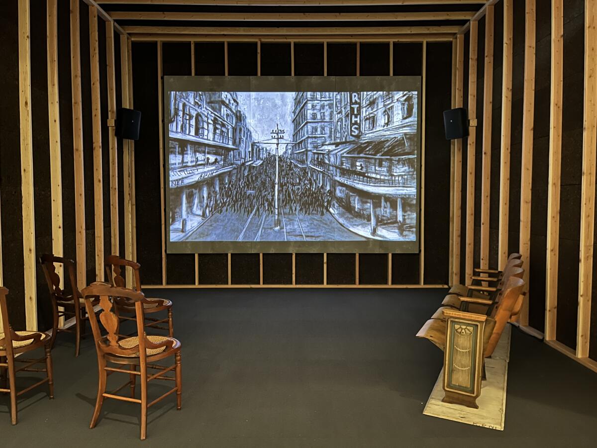 A stop-motion film is shown inside a wooden structure featuring seating that includes vintage chairs and theater seats.