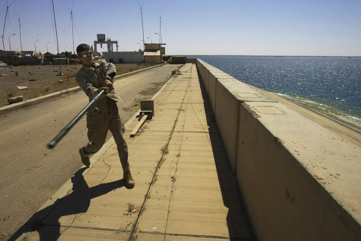In a photo from 2005, U.S. Marine Lance Cpl. Andrew Bickerstaff uses a tent pole to bat a rock off the Haditha Dam. The U.S. launched airstrikes near the western Iraq dam, targeting Islamic State insurgents.