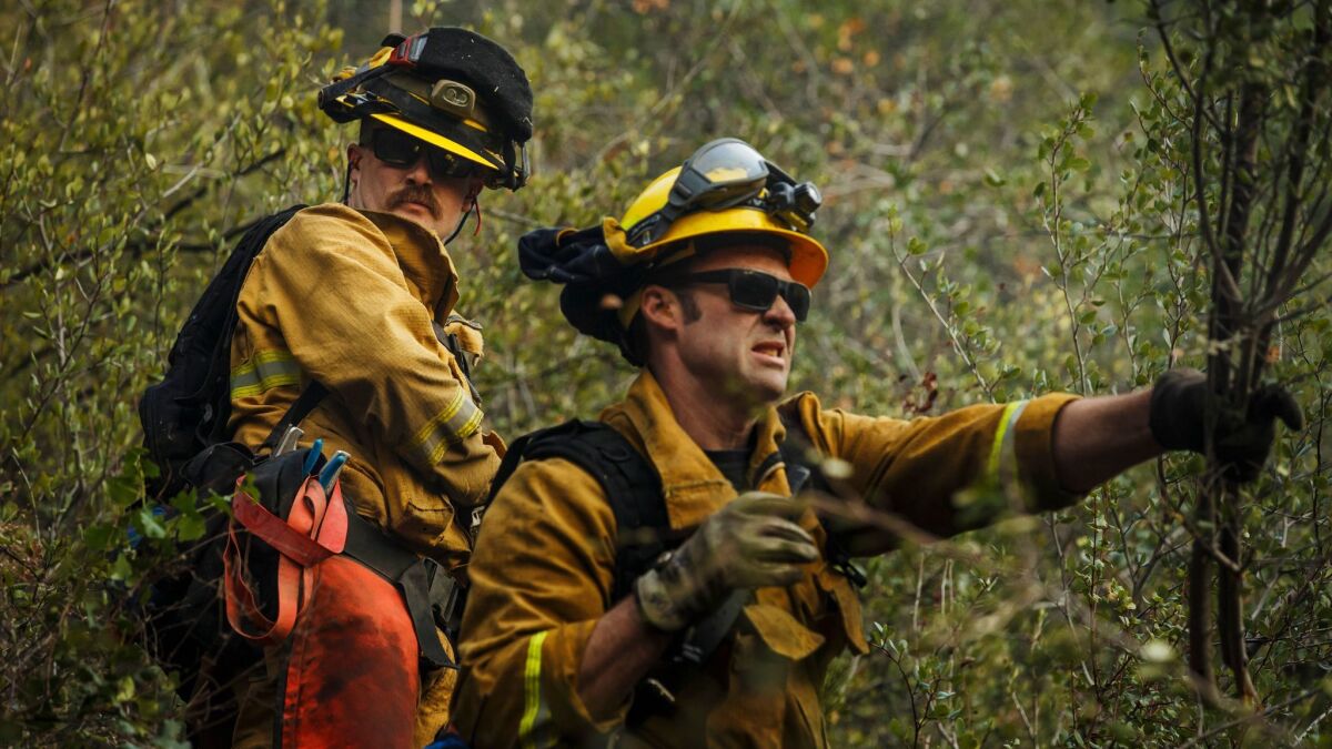 Alameda County firefighters Robert Groh, left, and Darryn Murphy clear brush as they work in the Santa Ynez Mountains on Sunday.