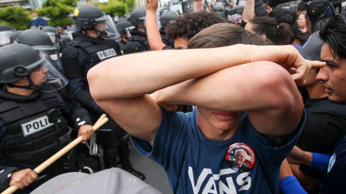 A protester covers his eyes as police try to clear the area after Trump supporters and anti-Trump protesters clashed after the then-presidential candidate held a rally at the San Diego Convention Center.