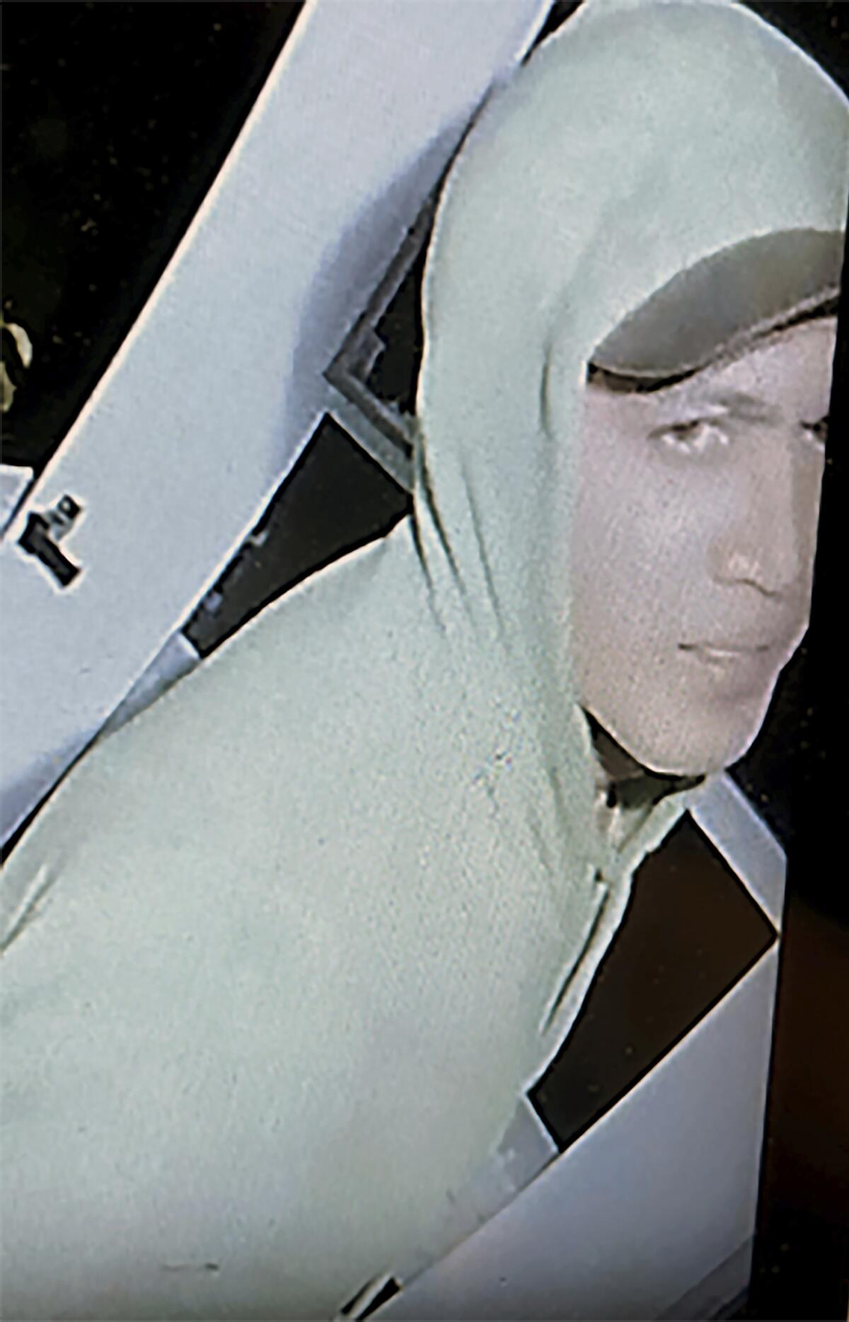 A man wears a hooded jacket over a cap.