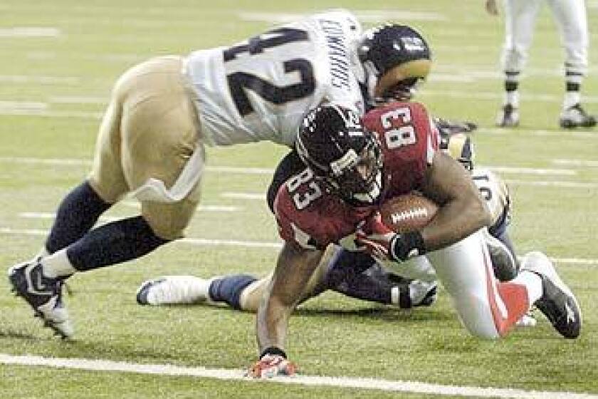 Atlanta Falcons tight end Alge Crumpler scores on an 18-yard touchdown reception under pressure from St. Louis Rams safety Antuan Edwards and safety Adam Archuleta.