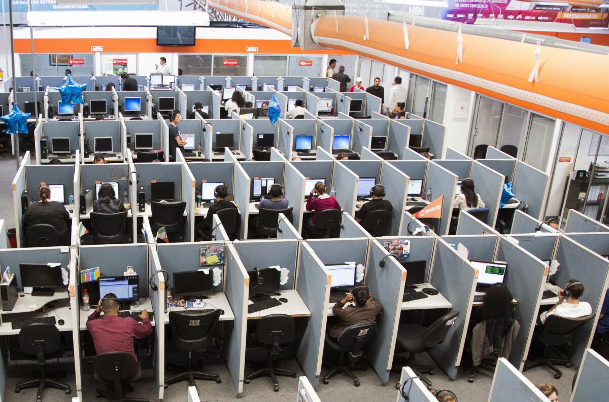 En esta imagen del 13 de agosto de 2015, se ven trabajadores sentados en sus escritorios en un centro de atención telefónica en la ciudad fronteriza de Tijuana, México. Si uno pasa todo el día sentado, tal vez quiera programar una caminata energética, solo para asegurarse de tener al menos una hora de pie. Los científicos analizaron datos de más de un millón de personas y encontraron que se requiere al menos entre 60 y 75 minutos de ejercicios de "intensidad moderada" para revertir el daño de pasar sentado al menos ocho horas al día. Encontraron que pasar sentado y no ejercitarse es tan dañino como la obesidad y el tabaquismo. (AP Foto/Alex Cossio, Archivo)