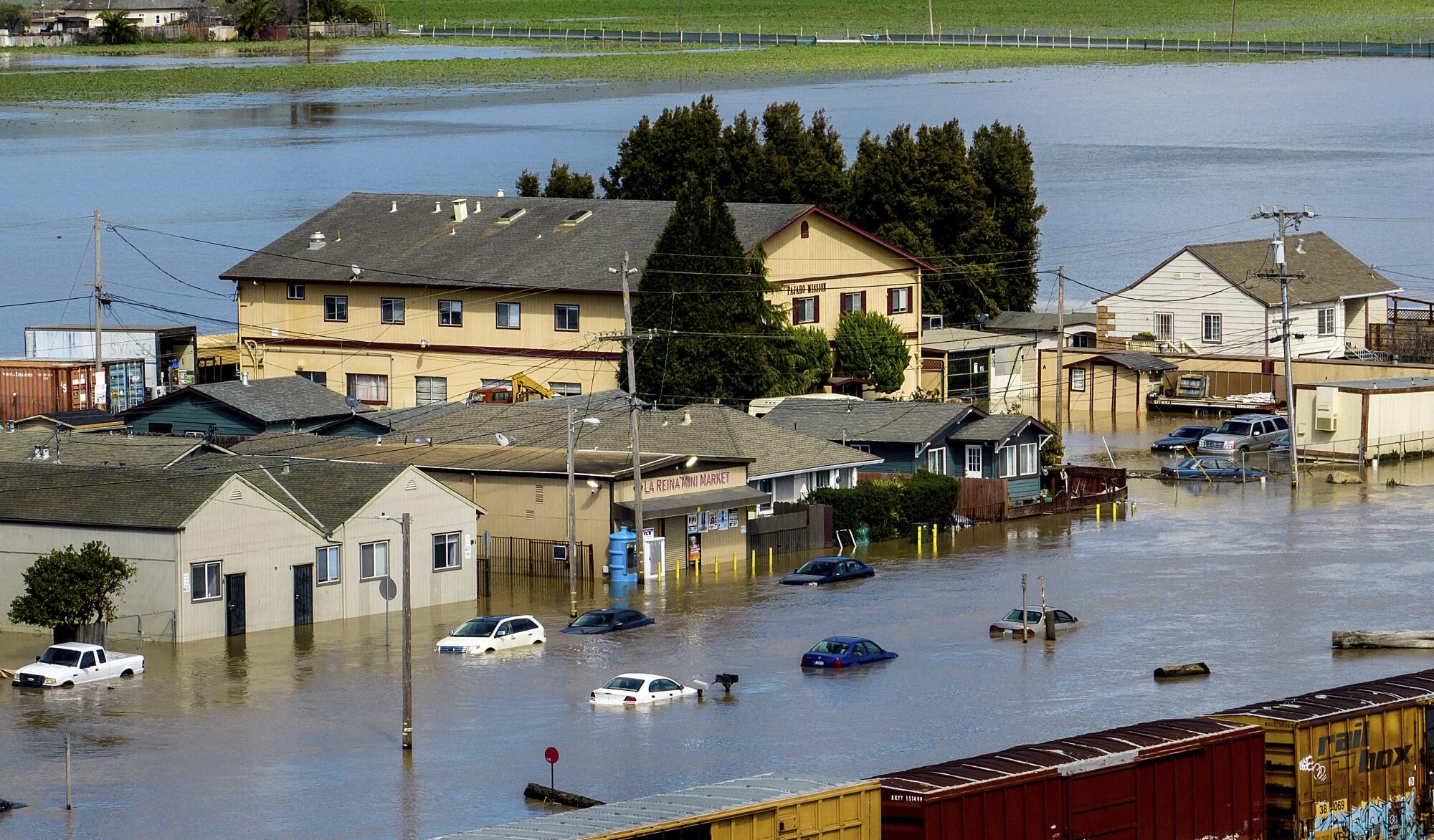Floodwaters surround homes and vehicles .