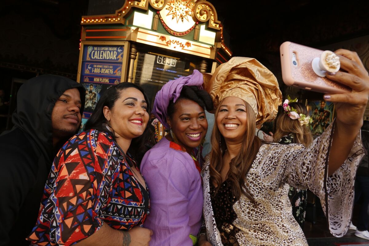 Moviegoer Cheyenne Martin, from right, takes a selfie with friends Chanell Jones-Harris, Lisa Lee and Play Bizness before attending a screening of the movie, "Black Panther," at El Capitan Theatre during opening weekend.