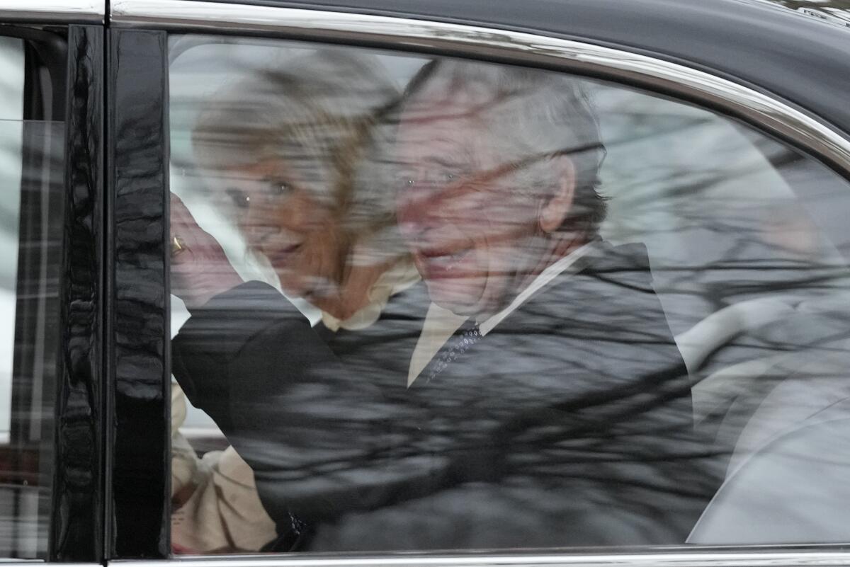 King Charles III and Queen Camilla ride in a car.