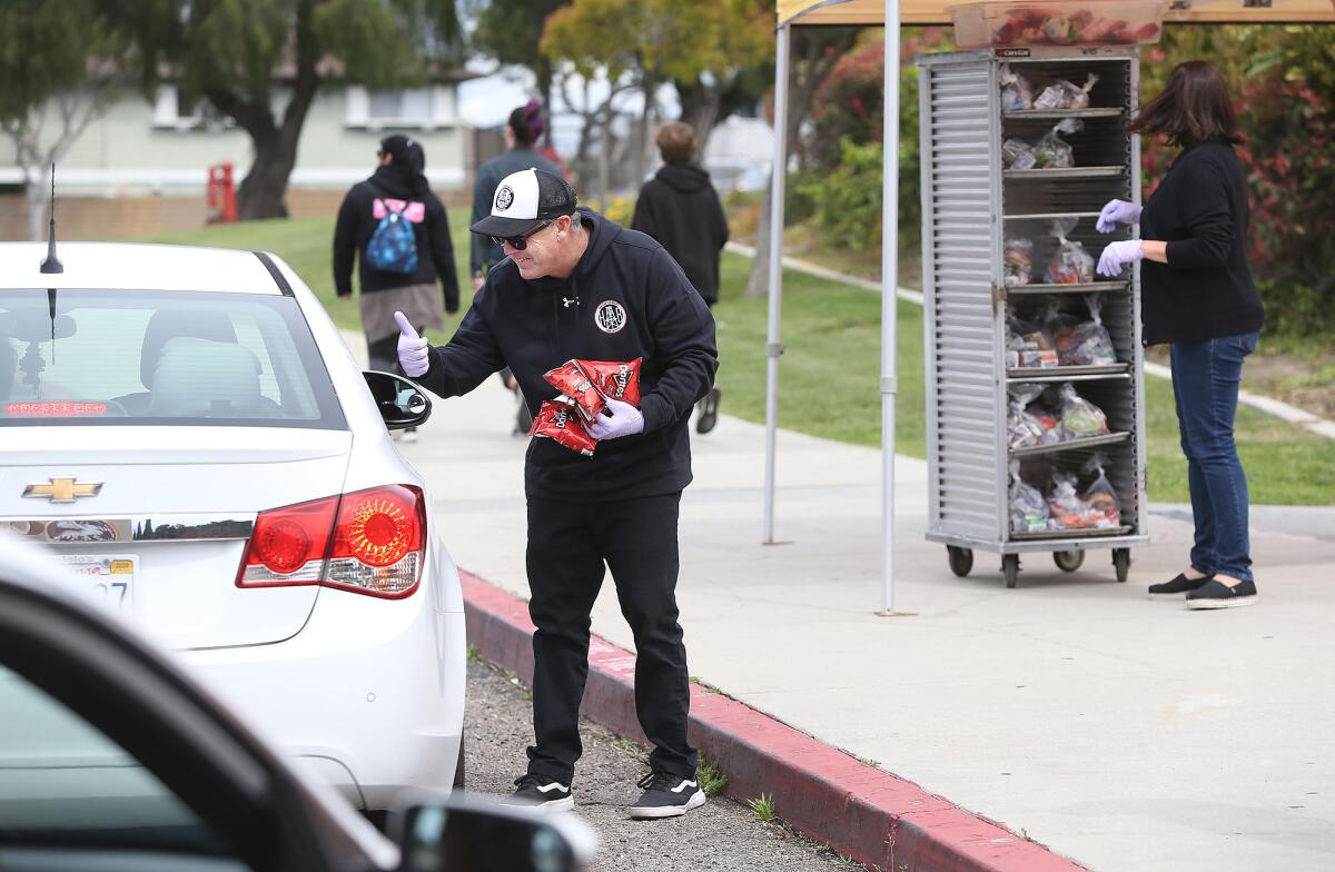 Danny Morris, principal of Huntington Beach High School, helps distribute "grab and go" lunches to students and their families as they drive up to Ocean View High on Friday in Huntington Beach.