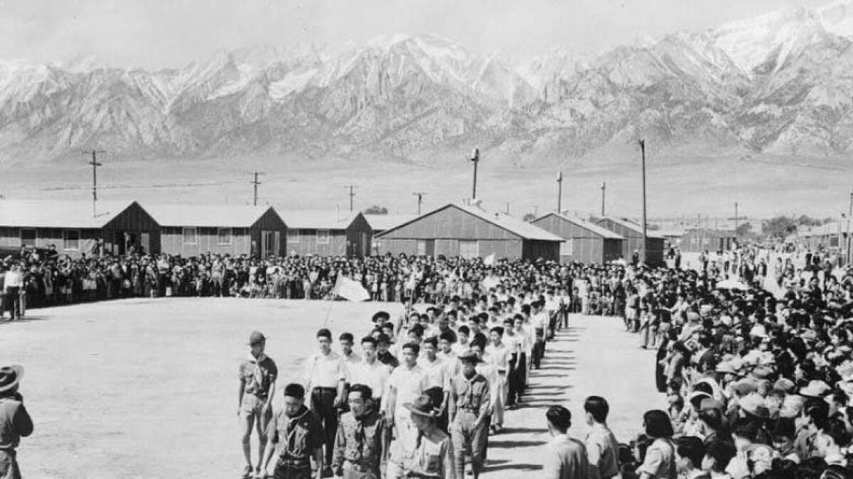 A black and white photo of Japanese Americans in a large yard at the Manzanar incarceration camp during World War II