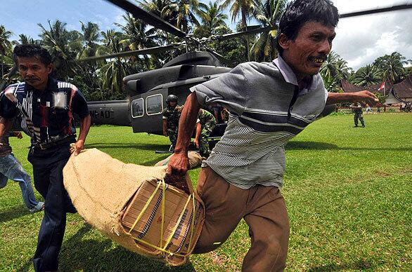 Residents carry food brought by an Indonesian military helicopter to isolated area hit by last week's earthquake. The West Sumatra disaster management coordination unit put the death toll from the quake at 448, with more than 2,000 others injured.