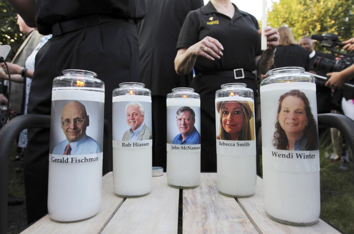 Pictures of five employees of the Capital Gazette newspaper adorn candles during a vigil.