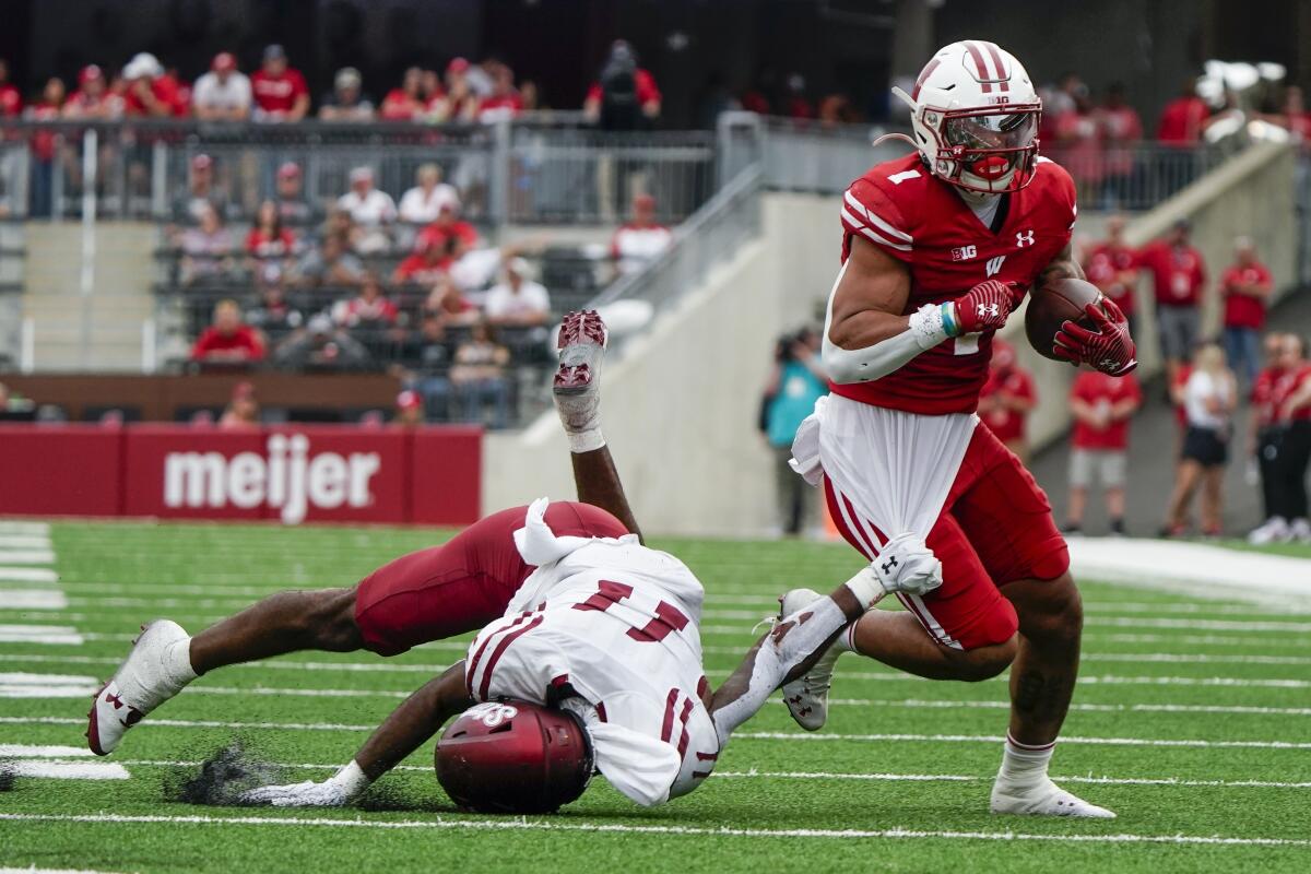 Wisconsin's Chez Mellusi (1) gets past New Mexico State's Dylan Early (11) during the first half of an NCAA college football game Saturday, Sept. 17, 2022, in Madison, Wis. (AP Photo/Morry Gash)