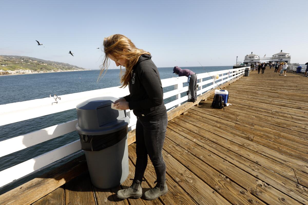 Zoë Kustritz puts stickers on Malibu Pier trash cans in the hope that her brother or someone who knows him will see them.