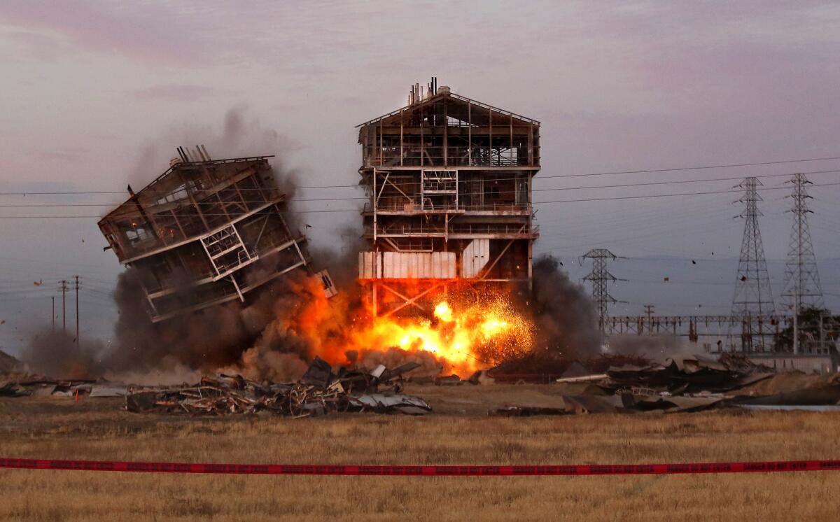 One tower falls as explosives that will bring down the other are detonated at an old Pacific Power and Electric power plant in Bakersfield. A man watching the demolition from 1,000 feet away was struck by flying debris and lost a leg, and others suffered injuries as well.