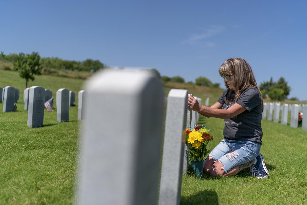 Barbie Rohde toca la lápida de su hijo, el sargento del Ejército Cody Bowman, en el cementerio nacional 
