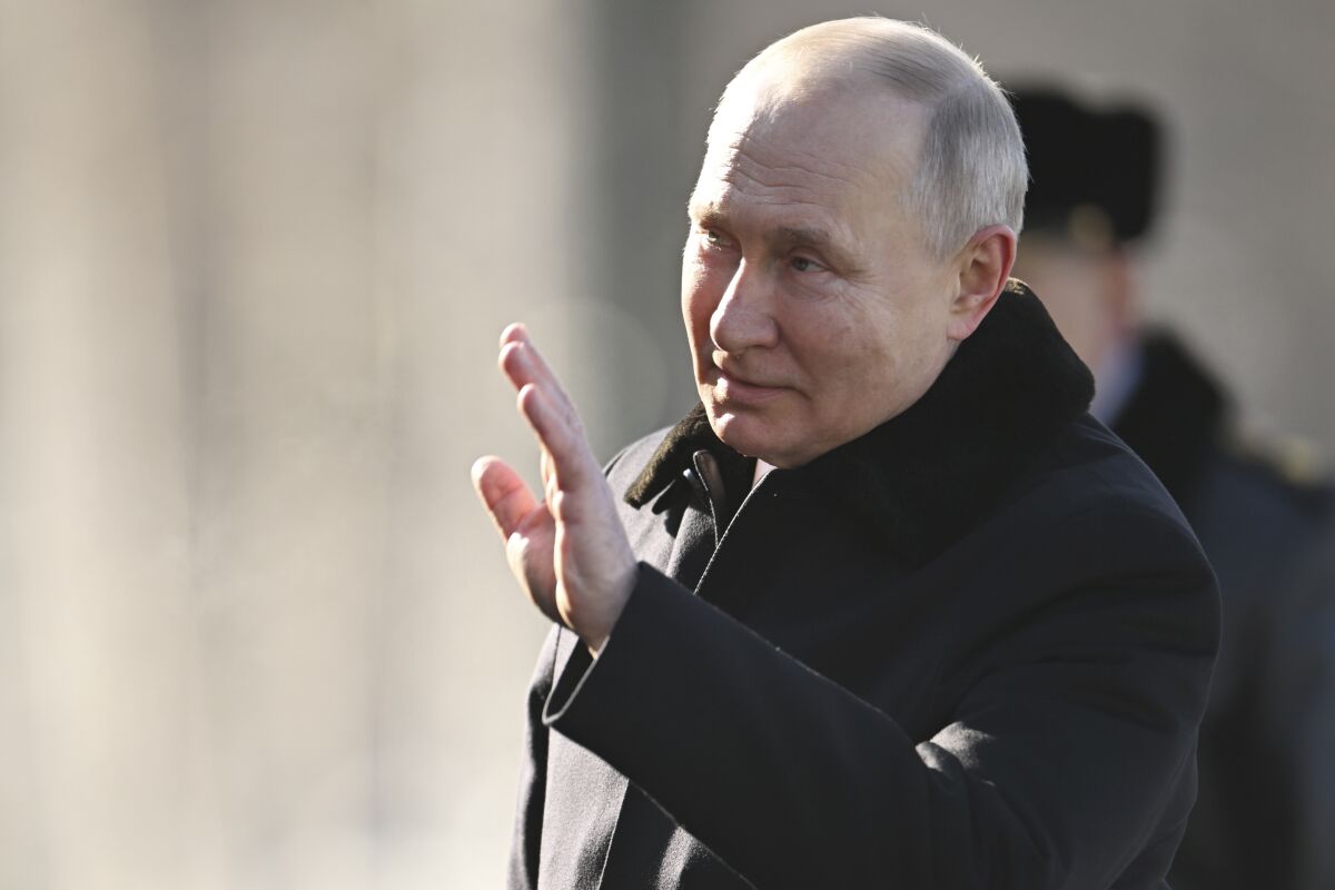 Vladimir Putin waving and wearing a black coat