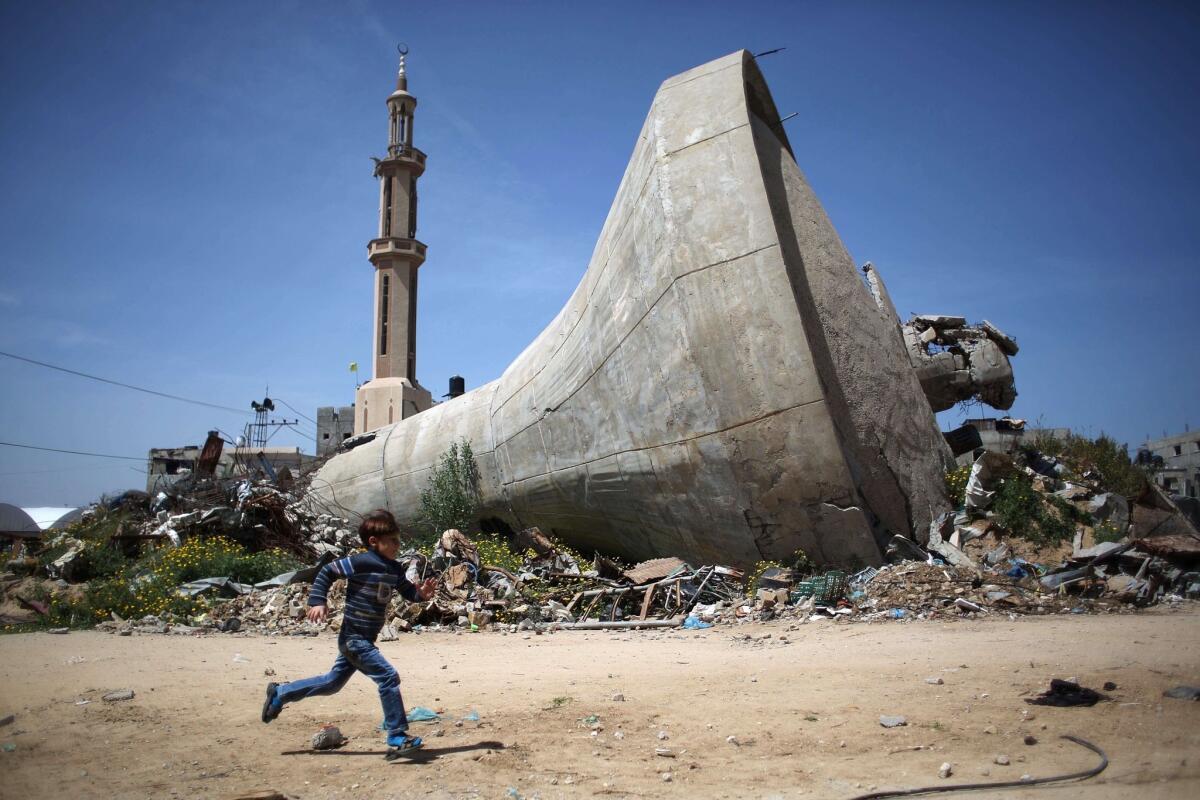 A Palestinian child runs past a water tank in southern Gaza Strip that was destroyed in Israeli bombing during the 50-day war between Israel and Hamas militants in the summer of 2014.
