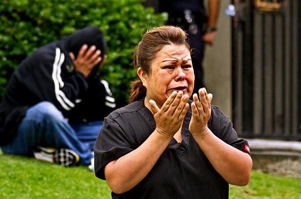In the wake of an apartment fire early Thursday that claimed the lives of 15-year-old twin boys, a family friend weeps in the foreground as the distraught father, Ronald Marroquin, sits with his head in his hands. See full story