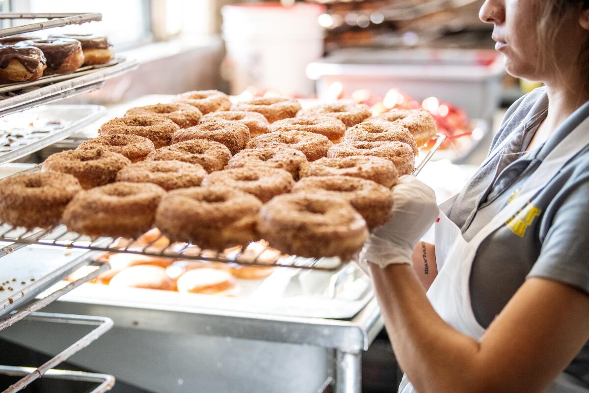 Jasmine Gonzalez moves a freshly made tray of doughnuts.
