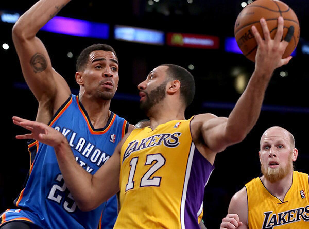 Lakers point guard Kendall Marshall (12) prepares to flip a pass behind Thunder guard Thabo Sefalosha to teammate Chris Kaman during play in the first half Thursday night at Staples Center.