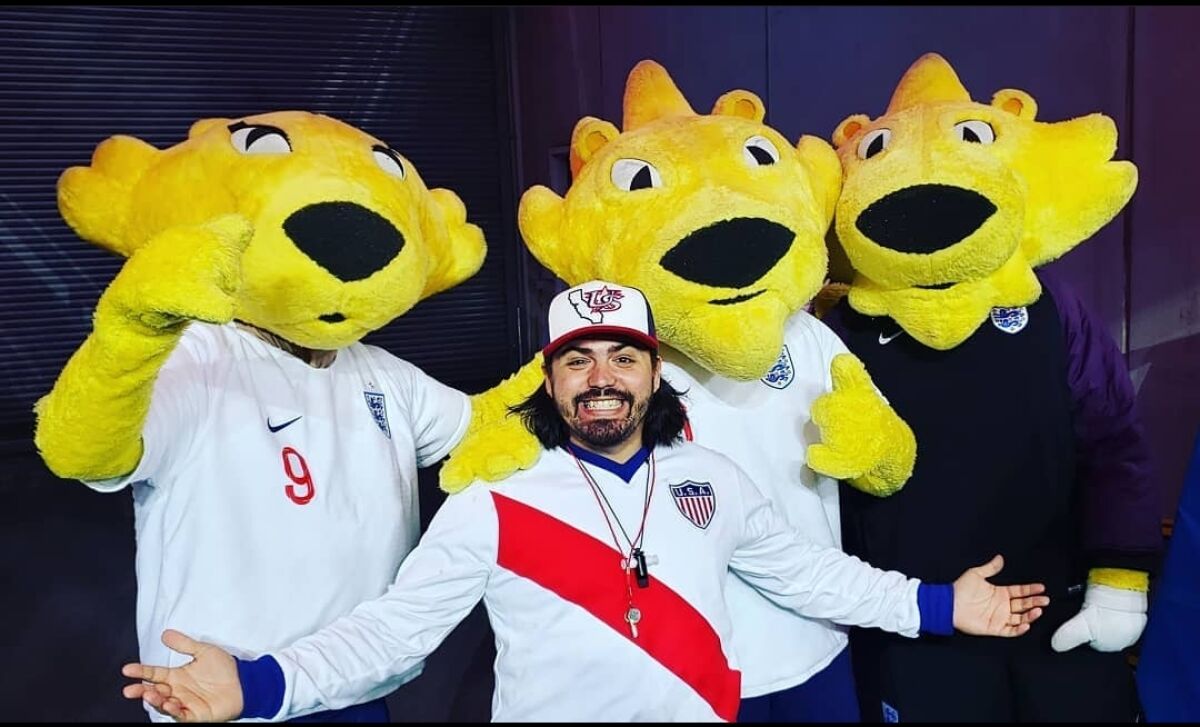 U.S. men's soccer fan Ray Noriega poses with mascots during one of his trips to support the team.