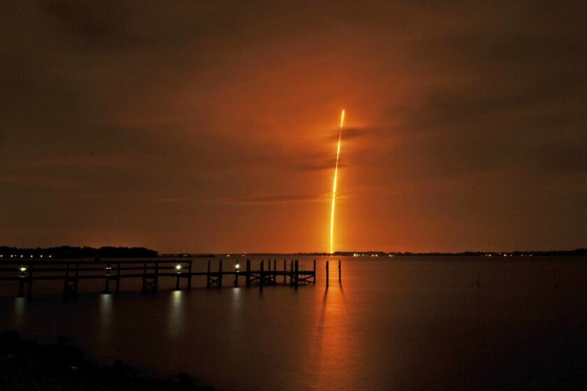 The SpaceX Falcon 9 launch appears in the distance from the back of a dockside restaurant along the Indian River in Florida.