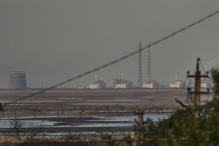 FILE - The Zaporizhzhia nuclear power plant, Europe's largest, is seen in the background of the shallow Kakhovka Reservoir after the dam collapse, in Energodar, Russian-occupied Ukraine, Tuesday, June 27, 2023. Ukraine and Russia accused each other Wednesday, July 5, 2023, of planning to attack the power plant, which is occupied by Russian troops, but neither side provided evidence to support their claims. (AP Photo/Libkos, File)