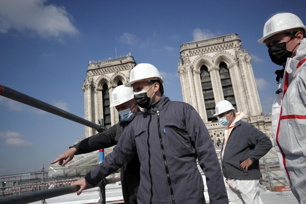 French President Emmanuel Macron visits the reconstruction site of the Notre-Dame cathedral Thursday, April 15, 2021 in Paris. Two years after a fire tore through Paris' most famous cathedral and shocked the world, French President Emmanuel Macron is visiting the building site that Notre Dame has become Thursday to show that French heritage has not been forgotten despite the coronavirus. (Benoit Tessier/Pool via AP)