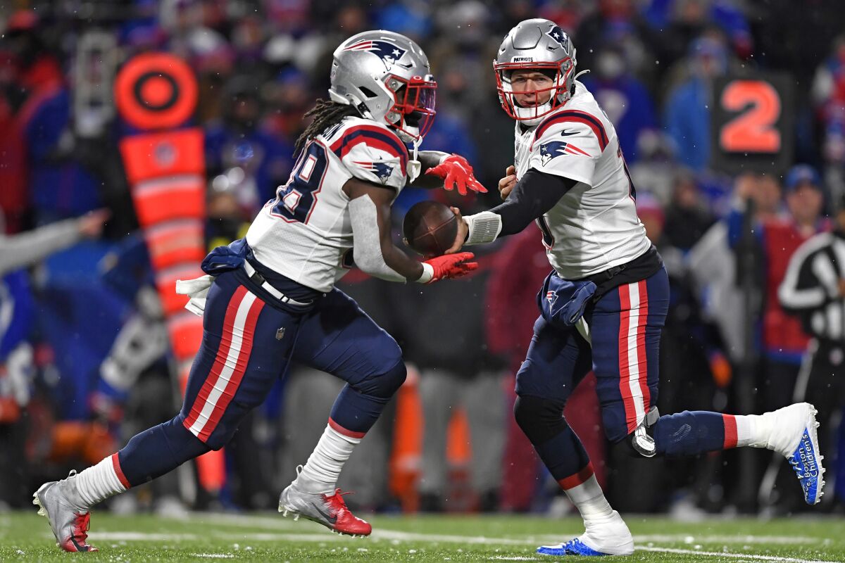 New England Patriots quarterback Mac Jones, right, hands off to running back Rhamondre Stevenson during the second half of an NFL football game in Orchard Park, N.Y., Monday, Dec. 6, 2021. (AP Photo/Adrian Kraus)