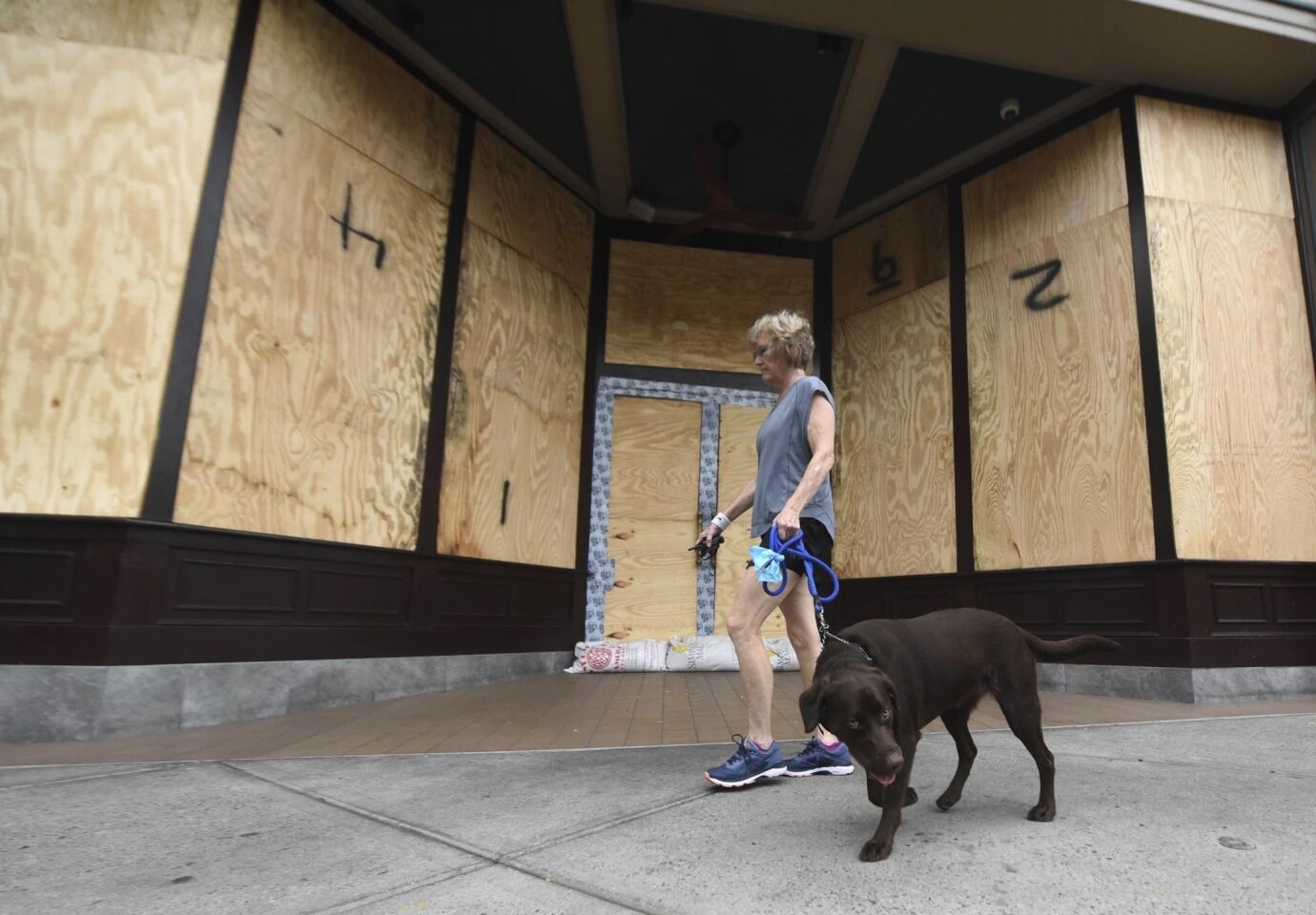 Deborah Covington walks his dog past Front Street Brewery in downtown Wilmington, N.C., Thursday, Sept. 13, 2018 ahead of Hurricane Florence.