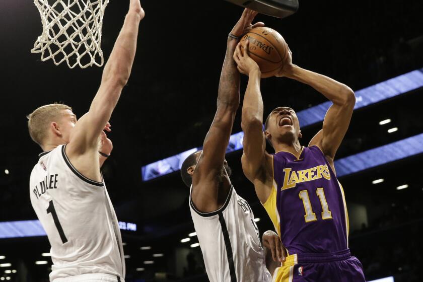Lakers forward Wesley Johnson, right, puts up a shot in front of Brooklyn Nets teammates Earl Clark, center, and Mason Plumlee during the first half of Sunday's game.