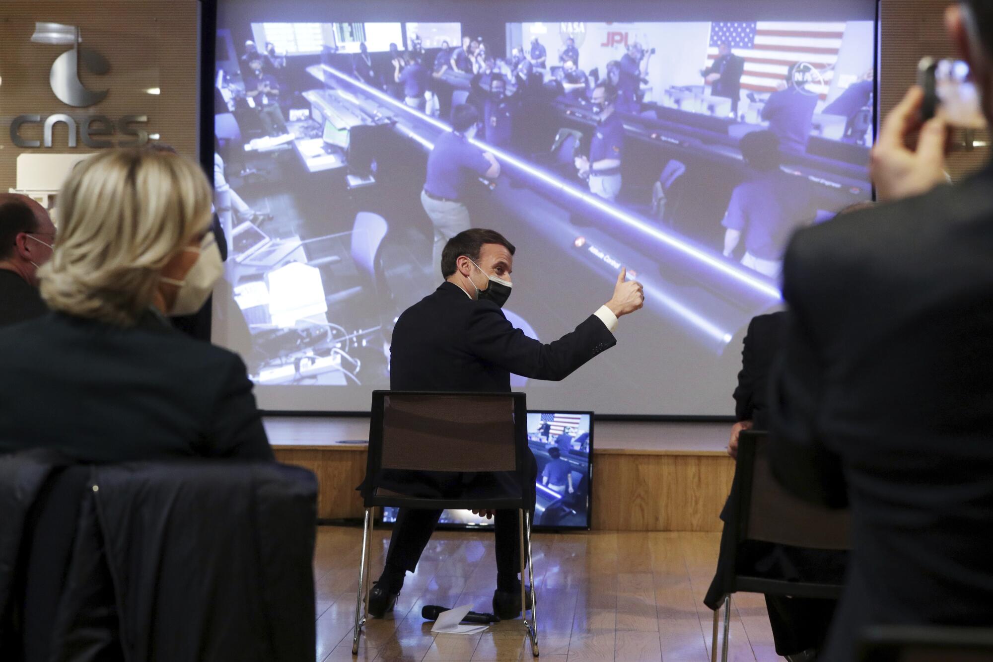 French President Emmanuel Macron and others sit in front of a projector screen