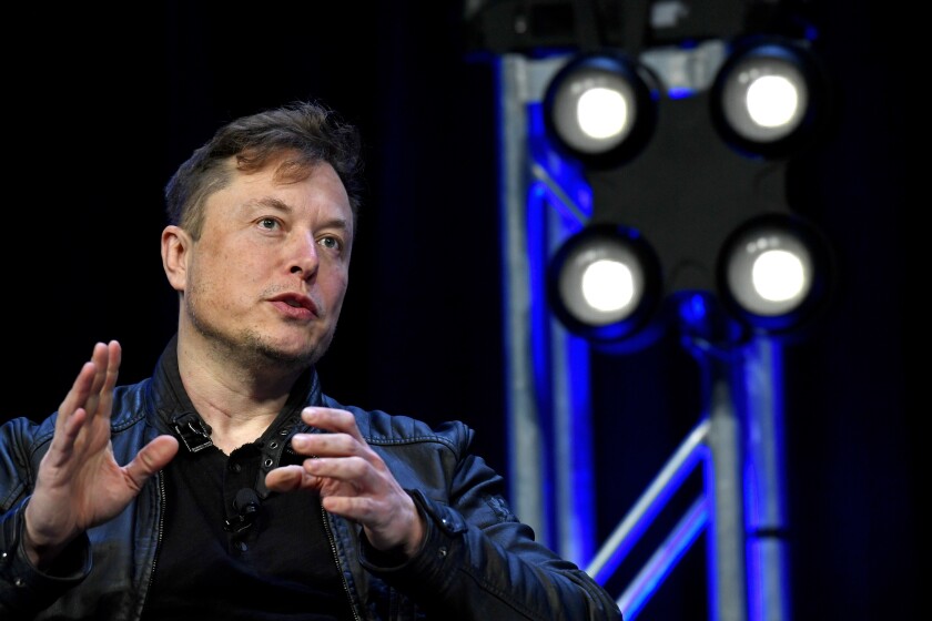Elon Musk, in a black shirt and jacket, gestures as he speaks