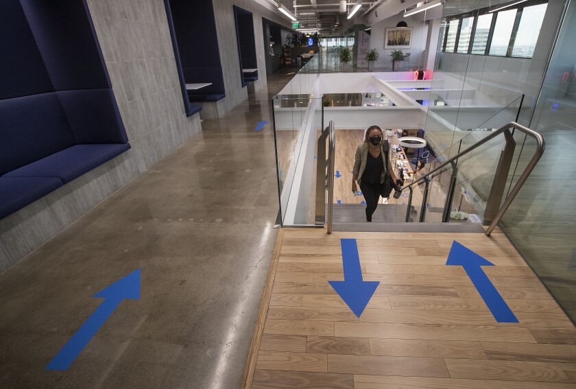 Arrows on a floor show the paths for coming and going as a woman walks up stairs.