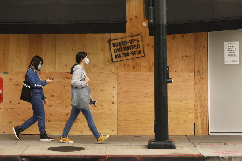 BEVERLY HILLS, CA - APRIL 02, 2020 Mask wearing pedestrians outside the boarded up Pottery Barn store located on Colorado Blvd in Pasadena Thursday morning April 02, 2020. Some businesses in Pasadena and Beverly Hills have boarded up the front of their stores during the coronavirus Covid-19 pandemic possibly to avoid vandalism during the crisis. (Al Seib / Los Angeles Times)