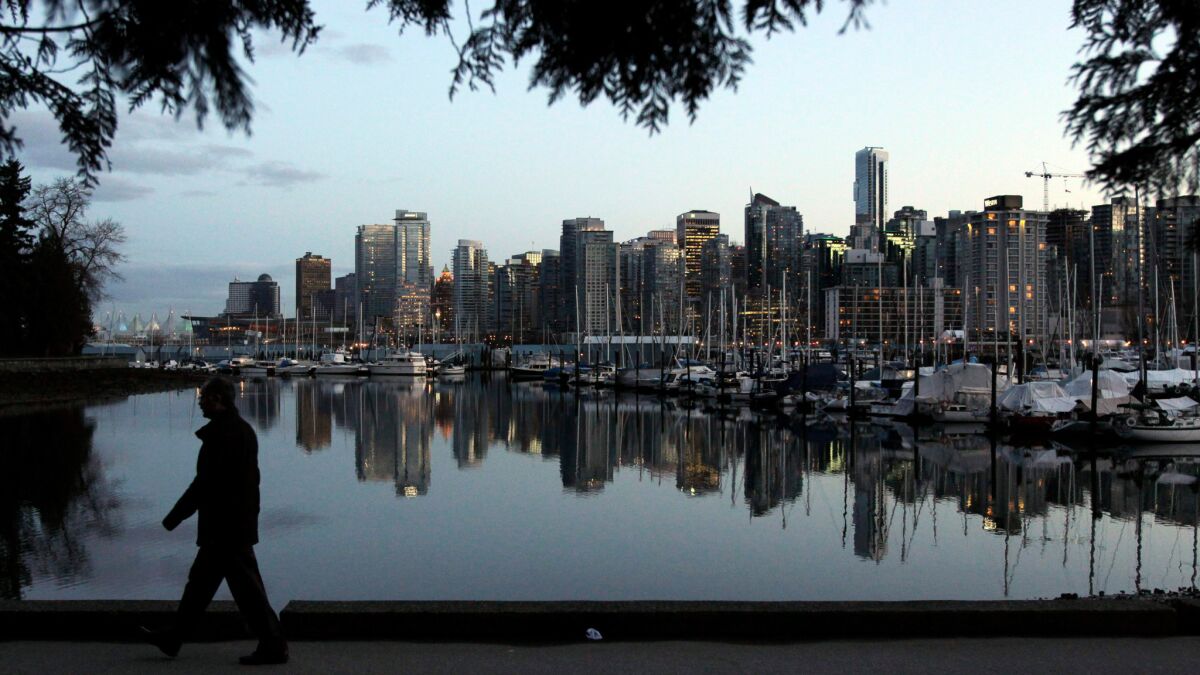 A man walks through Stanley Park as the Vancouver skyline is reflected in the water behind him on Feb. 5, 2010, one week before the start of the Vancouver 2010 Olympic Games.