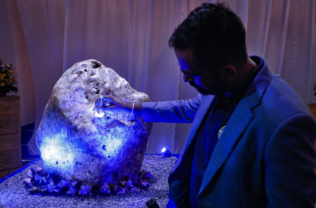 Chamila Suranga, a gemmology researcher attached to Gemological Institute of Ratnapura inspects a 310 kilograms (683 pounds) heavy natural corundum blue sapphire at a residence where it is kept in Horana, about 41 kilometers (25 miles) south of Colombo, Sri Lanka, Sunday, Dec. 12, 2021. A gem company in Sri Lanka has unveiled the massive gemstone that is certified as a rare and one of the biggest corundums found in the country and plans to offer it to museums and gem collectors. (AP Photo/Eranga Jayawardena)