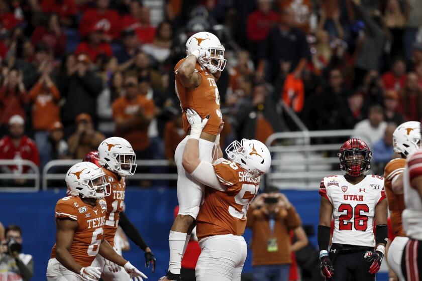 SAN ANTONIO, TX - DECEMBER 31: Zach Shackelford #56 of the Texas Longhorns lifts Collin Johnson #9 in celebration after a second quarter touchdown against the Utah Utes during the Valero Alamo Bowl at the Alamodome on December 31, 2019 in San Antonio, Texas. (Photo by Tim Warner/Getty Images)