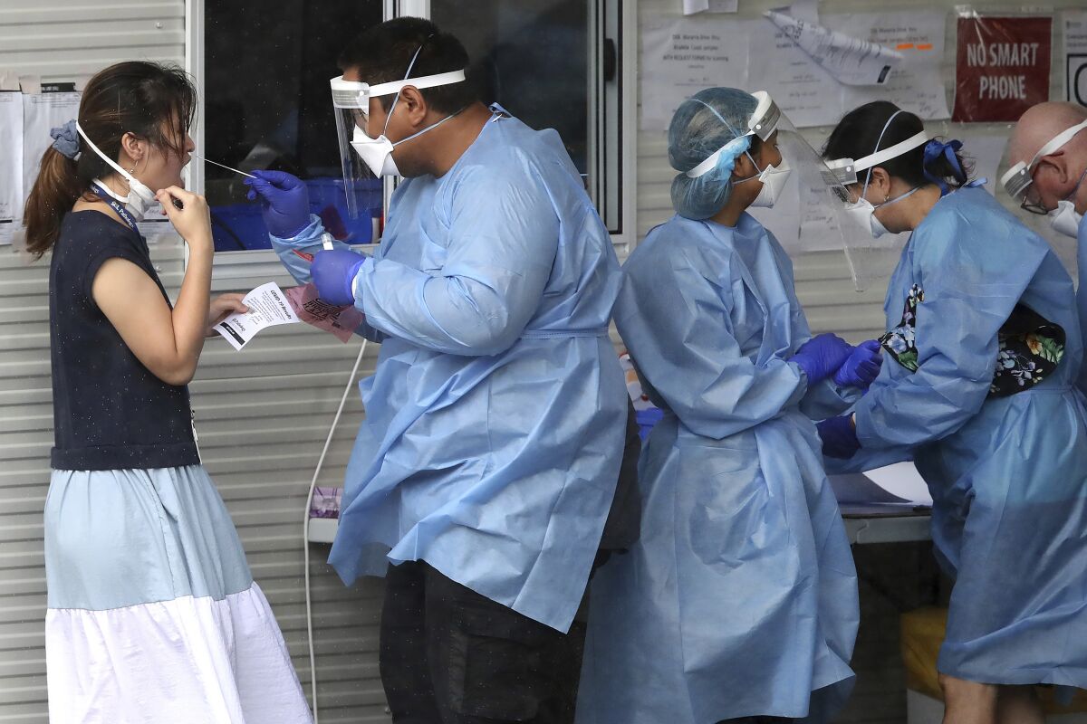 Health workers attend at a COVID-19 testing site in Brisbane, Australia Friday, Jan. 7, 2022. Australia’s most populous state reinstated some restrictions and suspended elective surgeries on Friday as COVID-19 cases surged to another new record. (Jono Searle/AAP Image via AP)