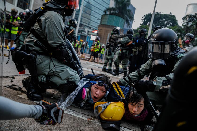 HONG KONG, CHINA -- SUNDAY, SEPTEMBER 29, 2019: Police officers in riot gear pin down young female protesters as they confront demonstrators with tear gas, batons and shields and make mass arrests near the HK Police Headquarters as chaos grips the city leading up to ChinaÕs National Day this week, in Hong Kong, on Sept. 29, 2019. Despite Chief Executive Carrie LamÕs bowing to the demonstratorsÕ key demand Ð withdrawal of a controversial extradition bill, pro-democracy demonstrators are now calling for Lam to immediately meet the rest of their demands. This includes an independent inquiry into policeÕs use of force, amnesty for those arrested, a halt on the use of the word ÒRiotÓ when describing the rallies, and lastly, calls for universal suffrage for the people of Hong Kong. (Marcus Yam / Los Angeles Times)