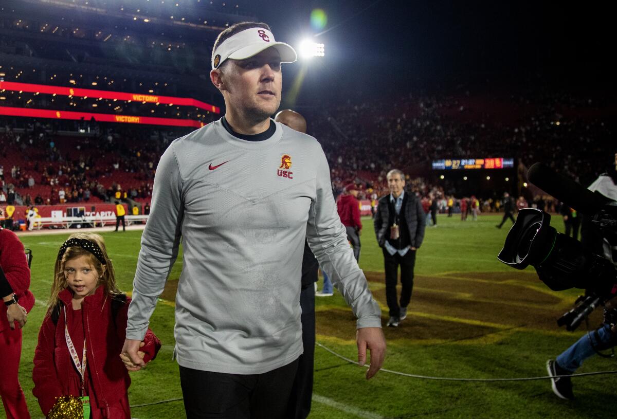 USC coach Lincoln Riley holds his daughter's hand as he leaves the field after the Trojans beat Notre Dame.