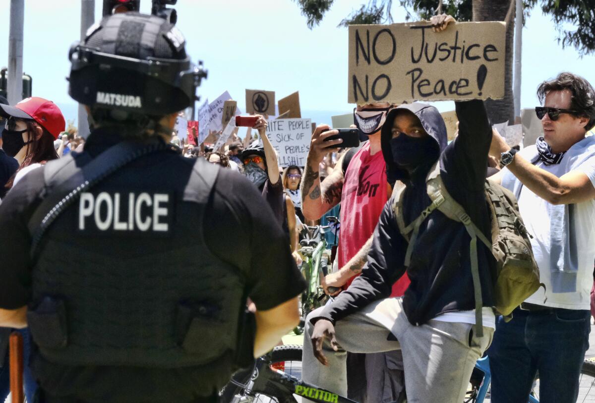 A police officer faces a crowd of protesters, some carrying signs. 