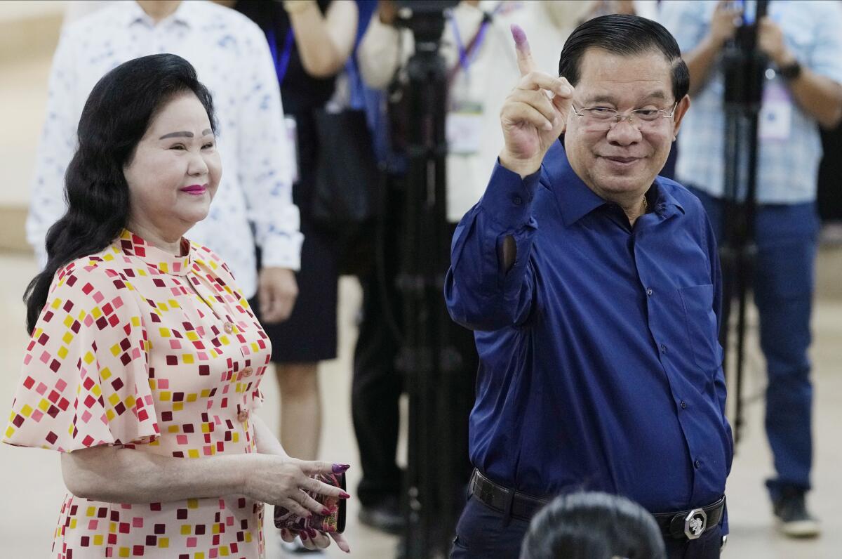 Cambodian Prime Minister Hun Sen raises an inked finger after voting.