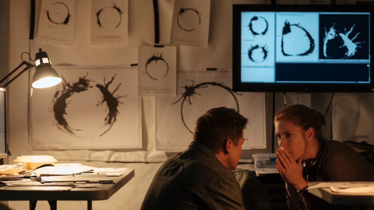 Jeremy Renner (as Ian Donnelly) and Amy Adams (linguist Louise Banks) sit before alien logograms in "Arrival." (Jan Thijs / Paramount Pictures)