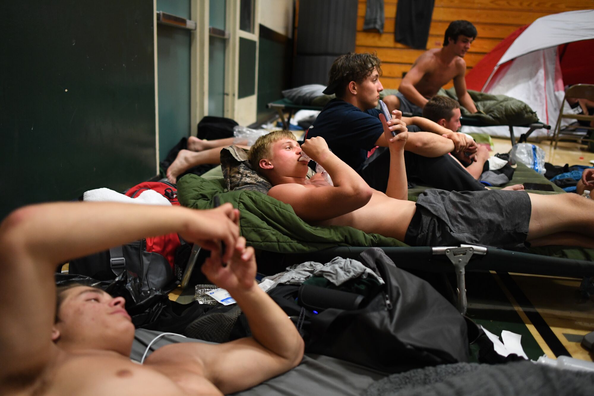 Paradise football players relax after practice as they spend the night in the school's gymnasium during summer training camp.