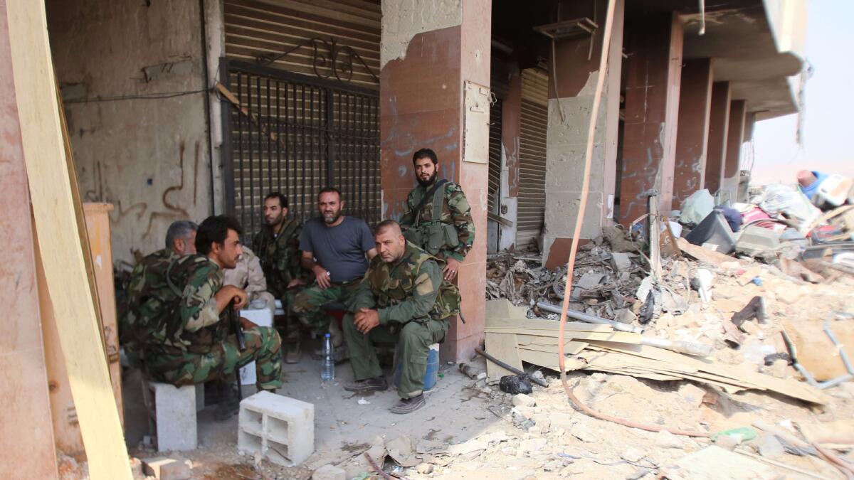 Syrian soldiers gather at the entrance of a damaged building in the government-controlled part of Darayya on Friday.